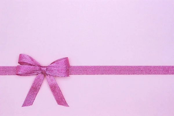 Ruban décoratif brillant avec noeud sur fond rose . — Photo