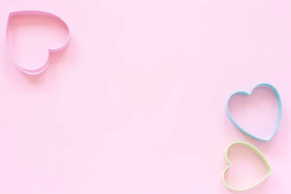 Coloridas galletas de corte en forma de corazón sobre fondo rosa pastel. Concepto tarjeta de San Valentín. Vista superior Copiar espacio para texto — Foto de Stock