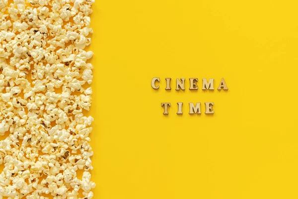 Borde de palomitas de maíz dispersas borde izquierdo y tiempo de cine sobre fondo de papel amarillo. Vista superior Copiar espacio Plantilla para texto o su diseño — Foto de Stock