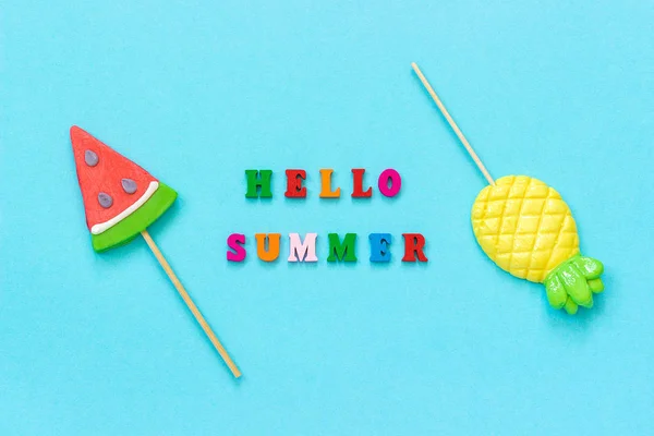 Hallo zomer kleurrijke tekst, ananas en watermeloen lollies op stok op blauw papier achtergrond. Concept vakantie of vakantie creatieve top weergave sjabloon wenskaart, briefkaart — Stockfoto