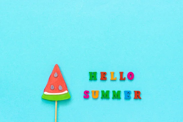 Hello nyár szöveget színes betűk és a görögdinnye nyalóka a botot a kék papír háttérben. Koncepció nyaralás vagy ünnepek Creative Top View térsablon másolása üdvözlőkártya, levelezőlap — Stock Fotó