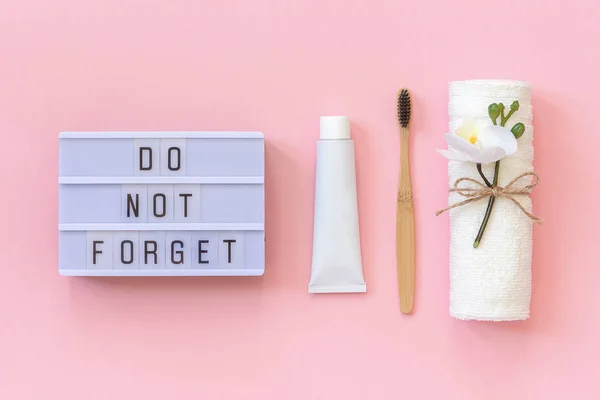 Texte de la boîte à lumière N'oubliez pas et brosse en bambou écologique naturelle pour dents, serviette, tube de dentifrice. Set pour le lavage sur fond rose. Concept soins dentaires Vue d'ensemble — Photo