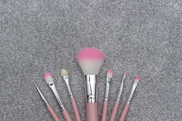 Set of pink makeup brushes on silver background. Template for text or your design. Flat lay Top view Copy space