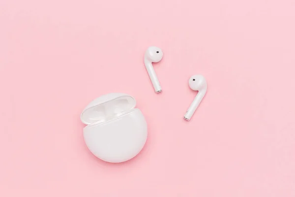 White wireless Bluetooth headphones and charging case on pink paper background — Stock Photo, Image