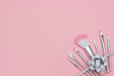 Pastel pembe arka plan üzerinde makyaj fırçaları ve kurdele serpantin whith yay seti. Metin veya tasarım şablonu. Üstte Görüntüle Kopyalama alanı