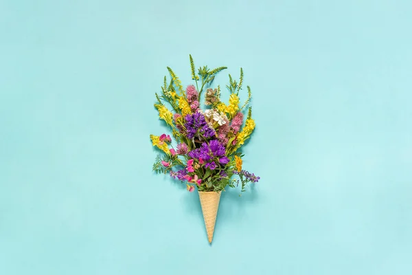 Bouquet field colored flowers in waffle ice cream cone on blue paper background Creative Flat Lay Top view Mock up Concept Women's day or Mothers Day Hello summer — Stock Photo, Image