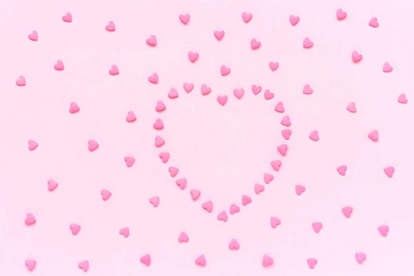 La confitería rosa espolvorea en forma de corazón sobre un fondo rosa pastel. Concepto tarjeta de San Valentín. Vista superior Copiar espacio para texto — Foto de Stock