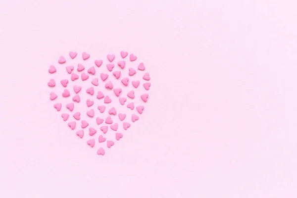 La confitería rosa espolvorea en forma de corazón sobre un fondo rosa pastel. Concepto tarjeta de San Valentín. Vista superior Copiar espacio para texto —  Fotos de Stock