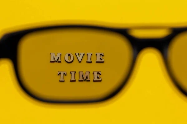 Enfoque en el texto Tiempo de la película a través de gafas 3D sobre fondo de papel amarillo. Concepto cine cine y entretenimiento — Foto de Stock