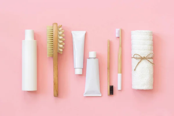 一套用于淋浴或沐浴的环保化妆品产品和工具 竹牙刷、天然刷子、白色瓶、用于身体、面部和牙齿护理的毛巾配件，背景粉红色。顶视图 平铺 — 图库照片