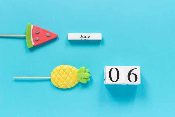 Calendario de cubos de madera fecha 06 de junio y frutas de verano caramelo piña, piruletas de sandía en palo sobre fondo azul. Concepto vacaciones o vacaciones Creative Top view Plantilla de laico plano — Foto de Stock