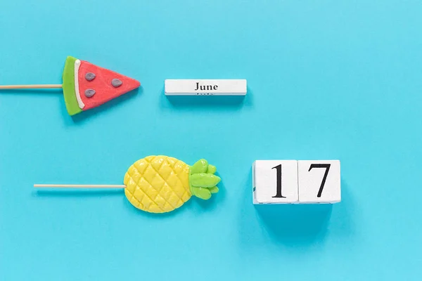 Calendario de cubos de madera fecha 17 de junio y frutas de verano caramelo piña, piruletas de sandía en palo sobre fondo azul. Concepto vacaciones o vacaciones Creative Top view Plantilla de laico plano — Foto de Stock