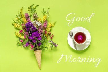 Waffle dondurma koni buket alan renkli çiçekler, yeşil kağıt arka plan üzerinde çay fincan Tebrik kartı Creative Top view Copy space Kavramı Günaydın