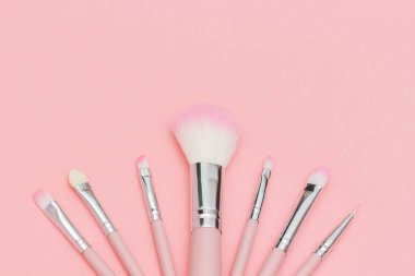Pastel pembe arka plan üzerinde pembe makyaj fırçaları seti