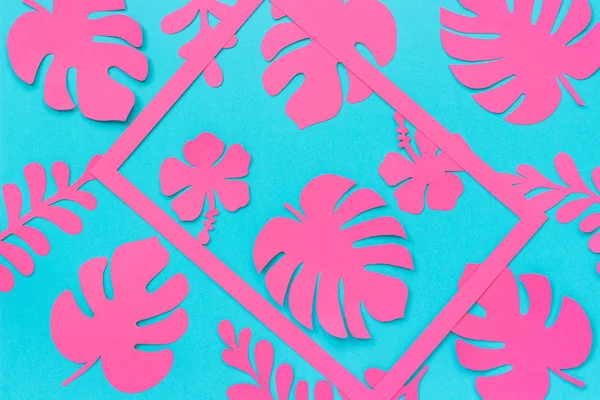 Tropical leaves pattern. Trendy pink tropical leaves of paper and frame on blue background. Flat lay, top-down composition, creative paper art