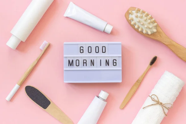 Cutie de lumină text Bună dimineața și set de produse cosmetice și instrumente pentru duș sau baie pe fundal roz. Conceptul de îngrijire a corpului de dimineață feminin, față, dinți pentru frumusețe și sănătate. Format Vizualizare de sus — Fotografie, imagine de stoc