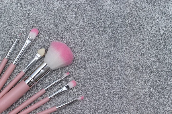 Set of pink makeup brushes on silver background