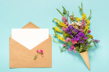 Buket alan renkli çiçekler waffle dondurma koni ve mavi arka plan Creative Flat Lay Top view Mock up Concept Women's day veya Anneler Günü metin için boş boş kağıt kart ile zanaat zarf