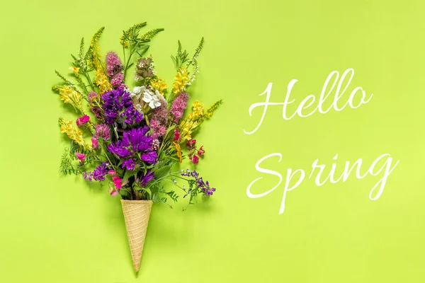 Text Hello Spring Bouquet field colored flowers in waffle ice cream cone on green paper background Creative Flat Lay Top view Concept springtime — Stock Photo, Image