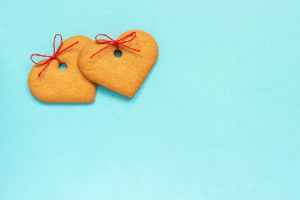 Galletas de jengibre en forma de corazón decoradas con un lazo sobre un fondo azul. Vista superior Copiar espacio Tarjeta San Valentín —  Fotos de Stock