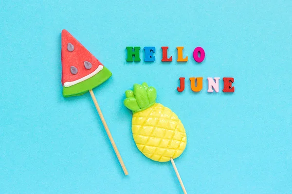 Hello June colorful text, pineapple and watermelon lollipops on stick on blue paper background. Concept vacation or holidays Creative Top view Template Greeting card, postcard — Stock Photo, Image