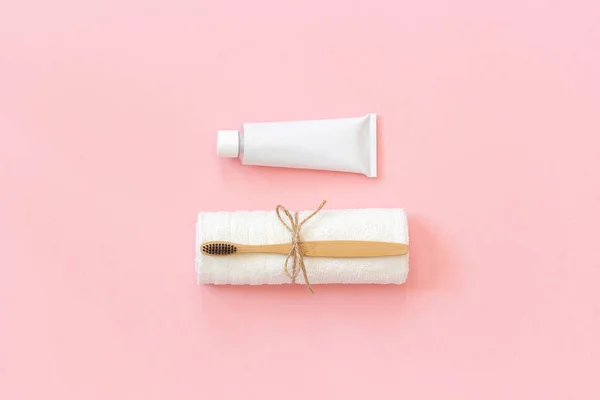 白色毛巾和牙膏管上的天然环保竹刷。设置在纸粉红色背景上清洗。复制文本或设计空间 顶部视图 平面布局 — 图库照片