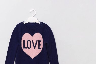 Desen pembe kalp ve gri arka plan üzerinde askı üzerinde yazıt Love ile Kadın mavi yün kazak. Kadın moda giyim kavramı bakmak. Kopyalama alanı