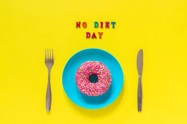 Texto NO DIETA DÍA, rosado donut en plato y cubiertos tenedor cuchillo de mesa. Concepto Día Internacional Sin Dieta, 6 de mayo — Foto de Stock