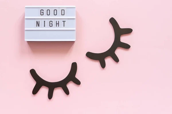 Lightbox text Good Night and decorative wooden black eyelashes, closed eyes on pink paper background. Concept Sweet dreams Greeting card Top view Creative flat lay — Stock Photo, Image