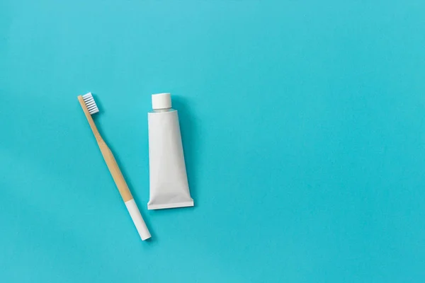 Spazzola di bambù ecologica naturale con setole bianche e tubo di dentifricio. Set per il lavaggio su sfondo blu carta. Copia lo spazio per il testo o il design Vista dall'alto Flat lay — Foto Stock