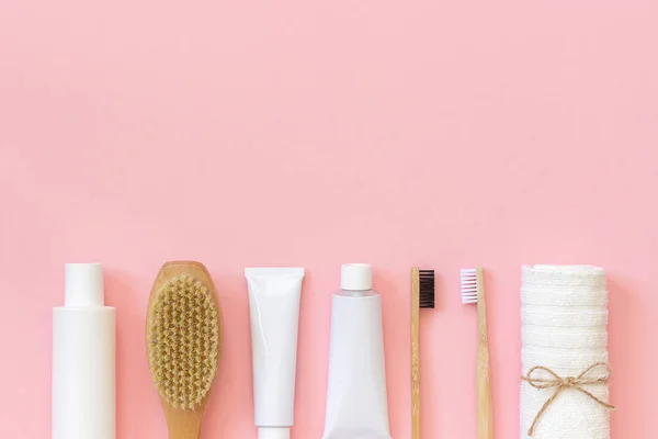 一套用于淋浴或沐浴的环保化妆品产品和工具 竹牙刷、天然刷子、白色瓶、用于身体、面部和牙齿护理的毛巾配件，背景粉红色。复制空间，顶视图 — 图库照片