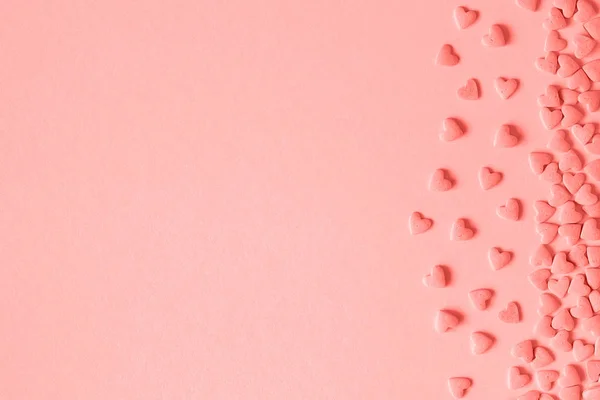 Hearts bonbons saupoudrer situé sur le côté droit sur fond rose dans un ton corail. Modèle pour carte de vœux, texte, conception, espace de copie — Photo