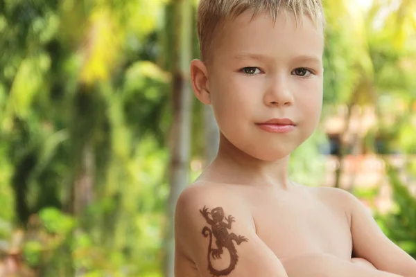 boy with a temporary tattoo of henna on his shoulder against the