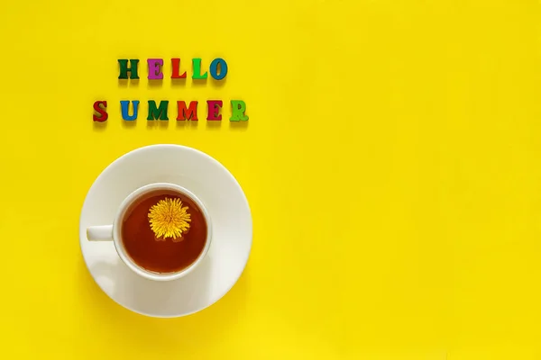 Testo Ciao estate, tazza di tè con dente di leone, Natura morta su sfondo giallo. Copia spazio, Layout piatto, Concetto vista dall'alto — Foto Stock