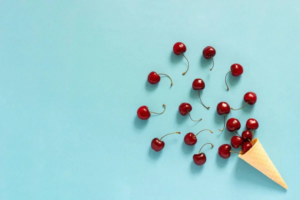 Gelato croccante al waffle con ciliegie rosse mature sparse. Natura morta su sfondo blu. Copia spazio, Posa piatta, Vista dall'alto, biglietto di auguri — Foto Stock