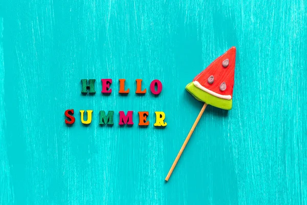 Hello Summer tekst z kolorowych liter i lizak arbuz na kij na drewnianym niebieskim tle. Koncepcja Creative Top widok szablon karta okolicznościowe — Zdjęcie stockowe