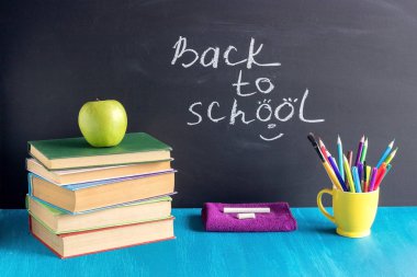 Okula ve öğrencilerin işyerine metin geri. Arka plan siyah tebeşir Kavramı Eğitim mavi masada Kitap kırtasiye elma tebeşir
