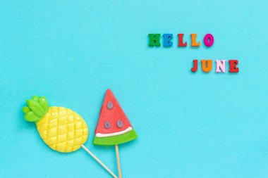 Merhaba renkli metin, ananas ve karpuz lolipop mavi Kağıt arka plan üzerinde sopa Haziran. Konsept tatil veya tatiller Creative top View Kopyala boşluk şablonu tebrik kartı, kartpostal