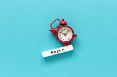Ağustosta tahta takvim ve mavi kağıtta kırmızı alarm saati. 