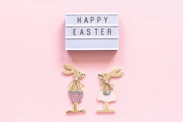 Texte Lightbox Joyeux Pâques et une paire de lapins en bois sur fond de papier rose. Concept Pâques Composition top-down créative Pose plate Carte de voeux — Photo