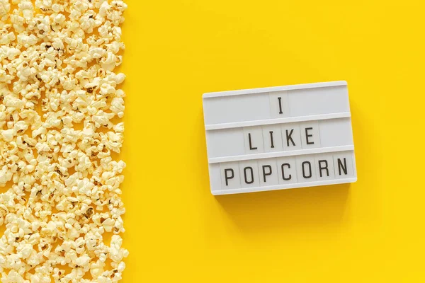 Rozházené popcorně levý okraj a text na světli mám rád popcorn na žlutém papíře. Šablona zobrazení nahoře — Stock fotografie