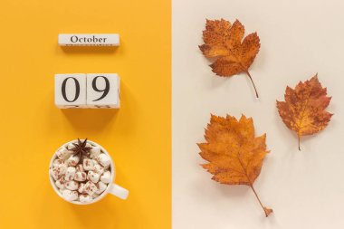 Sonbahar kompozisyon. Ahşap takvim 9 Ekim, şekerlemeler ve sarı sonbahar sarı bej arka planda yaprakları ile kakao fincan. Üst görünüm düz Lay mockup konsept Merhaba Eylül