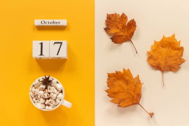 Sonbahar kompozisyonu. Ahşap takvim 17 Ekim, sarı bej arka plan üzerinde marshmallow si lik kakao ve sarı sonbahar yaprakları. Üstten düz yatıyordu Mockup Concept Merhaba Eylül