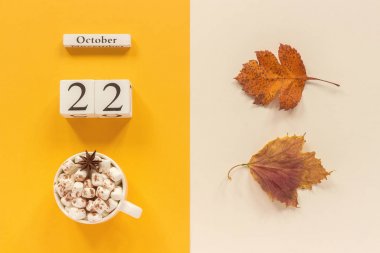 Sonbahar kompozisyonu. Ahşap takvim 22 Ekim, sarı bej arka plan üzerinde marshmallow si lik kakao ve sarı sonbahar yaprakları. Üstten düz yatıyordu Mockup Concept Merhaba Eylül
