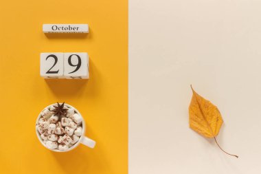 Sonbahar kompozisyonu. Ahşap takvim 29 Ekim, sarı bej arka plan üzerinde marshmallow si lik kakao ve sarı sonbahar yaprakları. Üstten düz yatıyordu Mockup Concept Merhaba Eylül