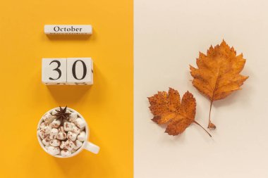 Sonbahar kompozisyonu. Ahşap takvim 30 Ekim, sarı bej arka plan üzerinde marshmallow si lik kakao ve sarı sonbahar yaprakları. Üstten düz yatıyordu Mockup Concept Merhaba Eylül