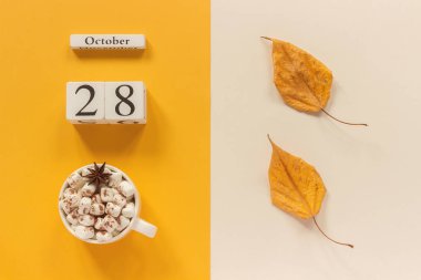 Sonbahar kompozisyonu. Ahşap takvim 28 Ekim, sarı bej arka plan üzerinde marshmallow si lik kakao ve sarı sonbahar yaprakları. Üstten düz yatıyordu Mockup Concept Merhaba Eylül