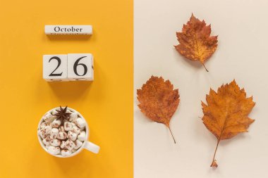 Sonbahar kompozisyonu. Ahşap takvim 26 Ekim, sarı bej arka plan üzerinde marshmallow si lik kakao ve sarı sonbahar yaprakları. Üstten düz yatıyordu Mockup Concept Merhaba Eylül