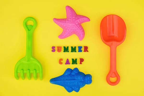 Text Summer camp and multicolored set children 's toys for summer games in sandbox or on sandy beach on yellow background. Креативный вид сверху Концепция детского отдыха и развития — стоковое фото