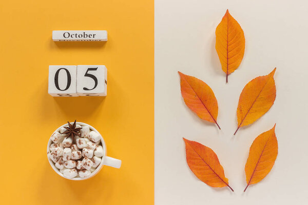 Autumn composition. Wooden calendar October 5, cup of cocoa with marshmallows and yellow autumn leaves on yellow beige background. Top view Flat lay Mockup Concept Hello September